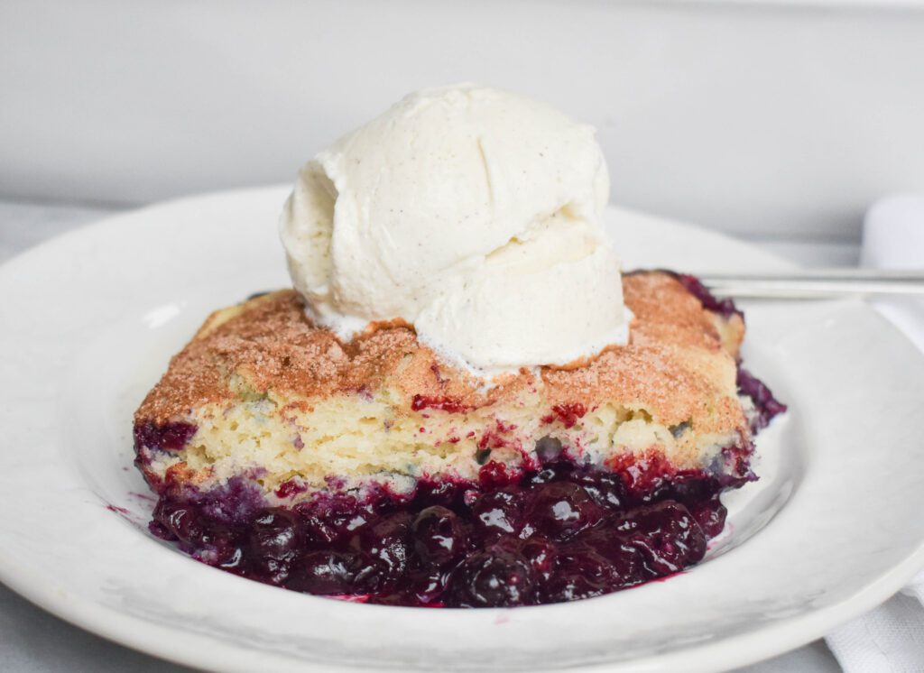 blueberry cobbler piece with ice cream on plate